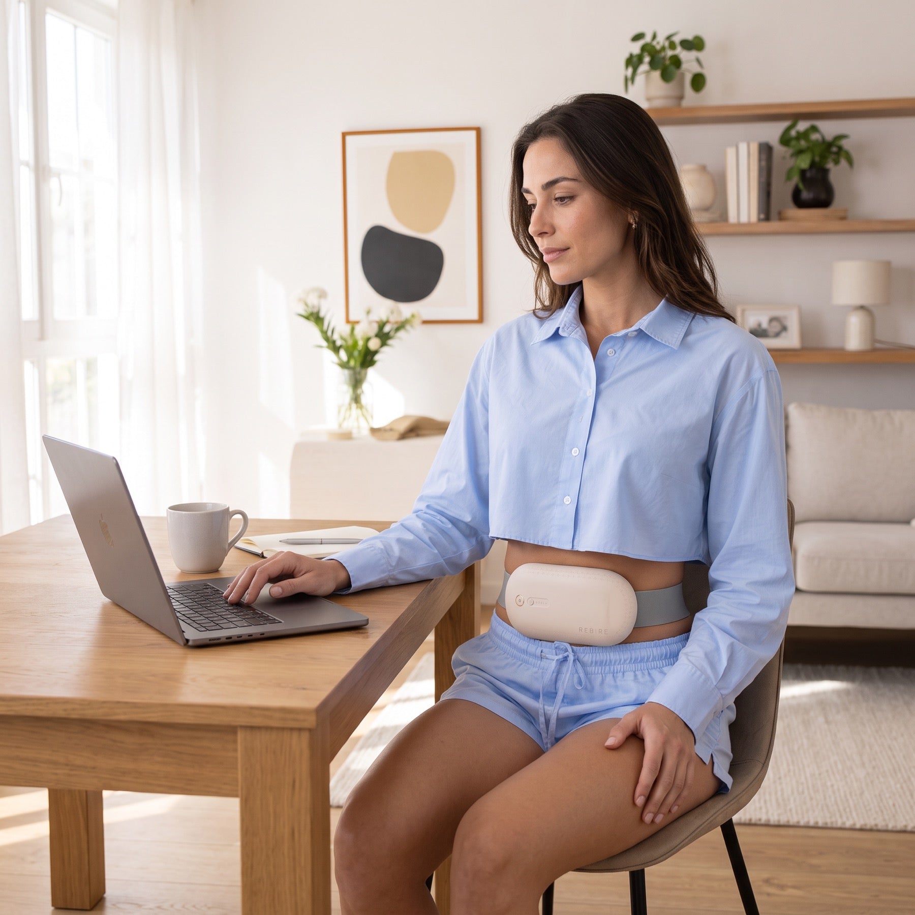 A woman working at a laptop, the NuFemme belt worn under her shirt